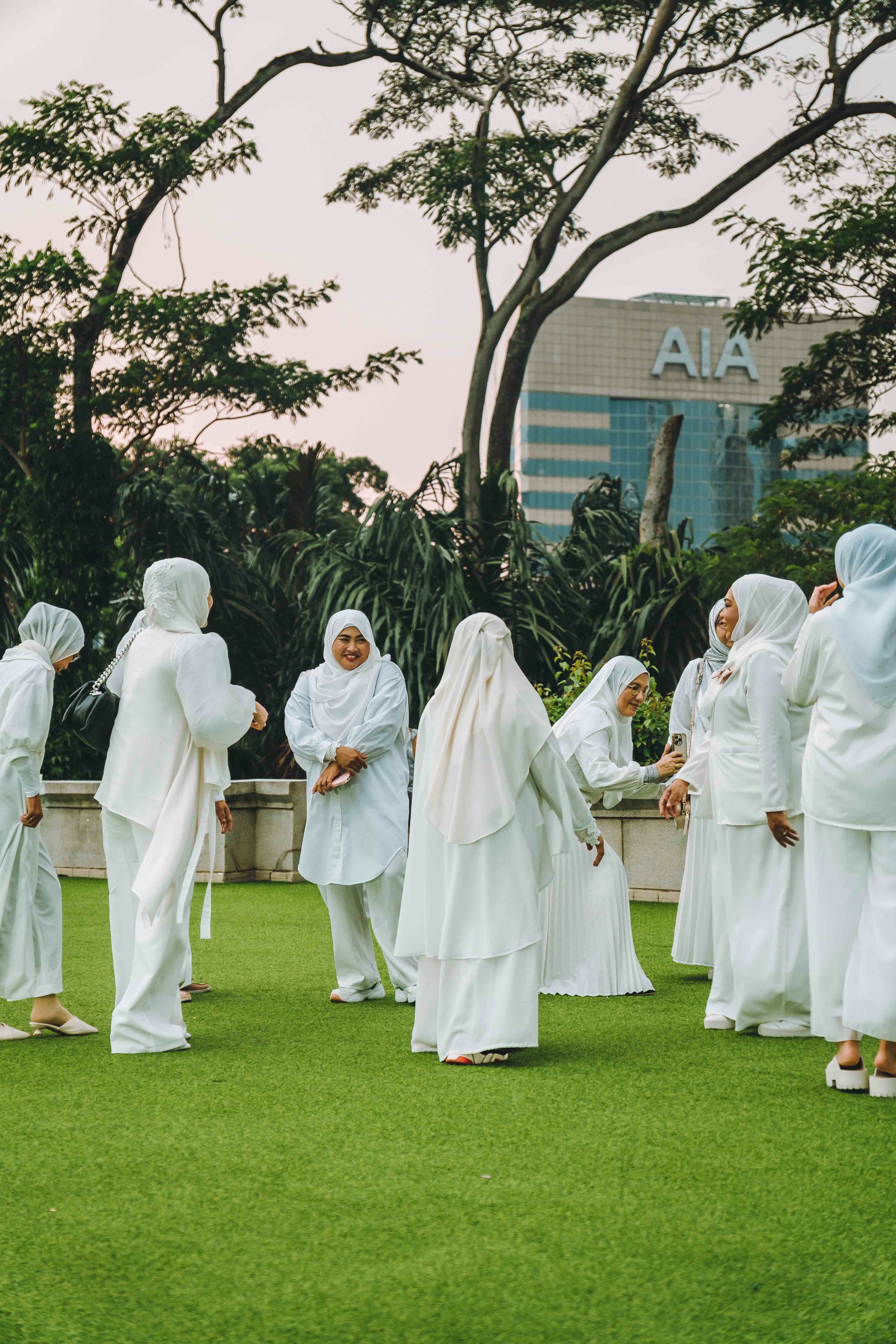 A group of women in white clothing gathering on a green lawn